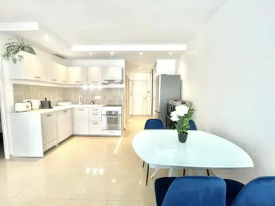 a white kitchen with a white table and blue chairs at Colony 2 in Cannes