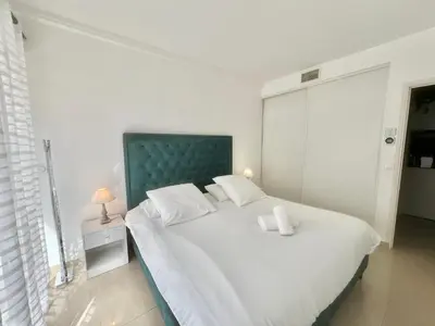 a bedroom with a large white bed with a green headboard at Colony 2 in Cannes