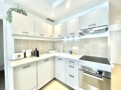a white kitchen with white cabinets and appliances at Colony 2 in Cannes