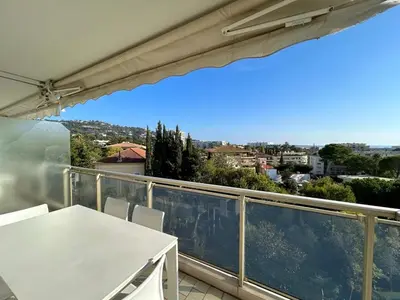 a balcony with a table and a view of a city at A013-Apt vue mer avec piscine et terrasse in Cannes