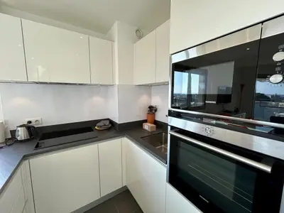 a kitchen with white cabinets and a black appliance at A013-Apt vue mer avec piscine et terrasse in Cannes