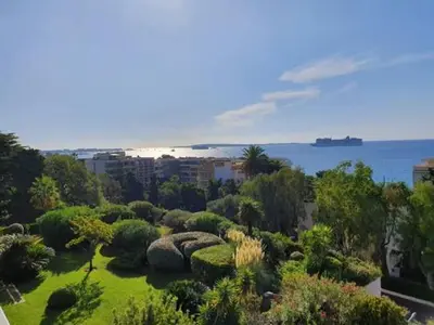 a garden with bushes and trees and the ocean at A069-Apt in residence with pool and sea view - Cannes in Cannes