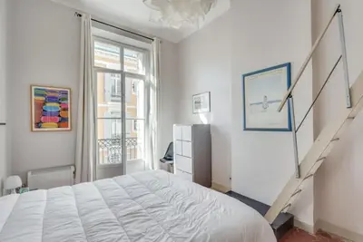 a white bedroom with a bed and a staircase at A084-Welcoming apartment in Rue d'Antibes the heart of Cannes in Cannes