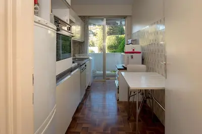 a kitchen with white appliances and a wooden table at A081-Cannes Appartement avec terrasse au calme in Cannes