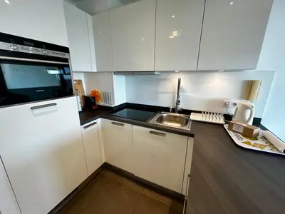 a white kitchen with a sink and a refrigerator at A018-Large studio with sea view swimming pool garage in Cannes