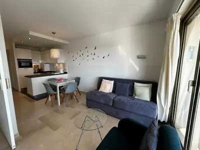 a living room with a blue couch and a table at A018-Large studio with sea view swimming pool garage in Cannes