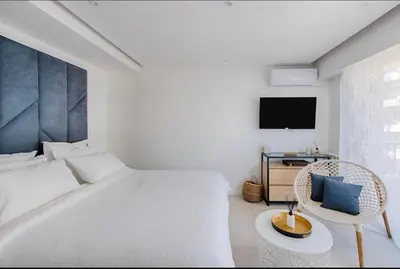 a white bedroom with a bed and a chair and a tv at B045-Studio croisette AC close Congress center SEA in Cannes
