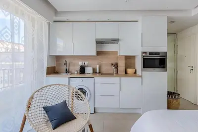 a kitchen with white cabinets and a blue pillow on a chair at B045-Studio croisette AC close Congress center SEA in Cannes