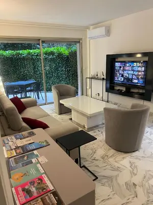 a living room with a couch and a table and a tv at Chic 47m2, 2 rooms, ground floor, nice patio, 280m beach Croisette in Cannes