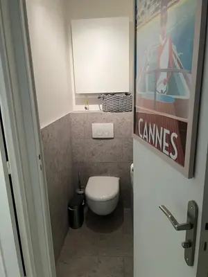 a small bathroom with a toilet and a poster on the wall at Chic 47m2, 2 rooms, ground floor, nice patio, 280m beach Croisette in Cannes