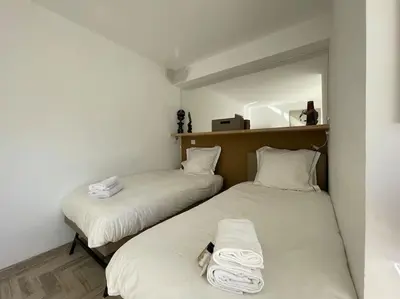 two beds in a small room with white sheets at L'Olivier - Croisette Martinez, Studio sur cour, plage 1 min in Cannes