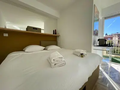 a bedroom with a large white bed with towels on it at L'Olivier - Croisette Martinez, Studio sur cour, plage 1 min in Cannes
