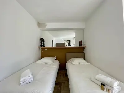 two beds in a small room with a mirror at L'Olivier - Croisette Martinez, Studio sur cour, plage 1 min in Cannes