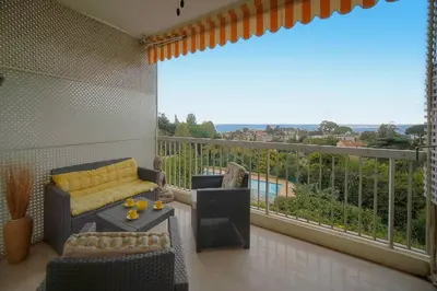 a living room with a balcony with a couch and chairs at MIPIM HORIZONS Executive Sea View Apartment 2 Bedrooms Terrace Pool Parking in Cannes