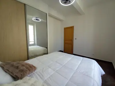a bedroom with a large white bed with a large mirror at Simon Apartments in Cannes