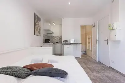a white room with a large bed and a kitchen at Simon Apartments in Cannes