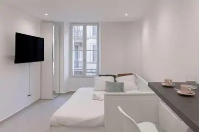 a white room with a bed and a flat screen tv at Simon Apartments in Cannes