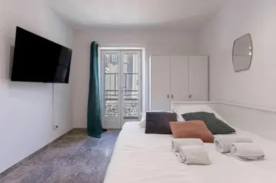 a room with a large white bed with a flat screen tv at Simon Apartments in Cannes