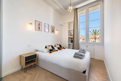 a white bedroom with a large bed and a window at The Palm - 5mn Palais - Croisette - Beaches in Cannes