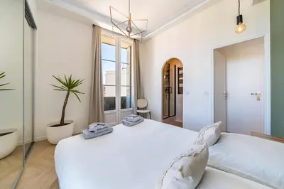 a white bedroom with a large bed and a potted plant at The Palm - 5mn Palais - Croisette - Beaches in Cannes