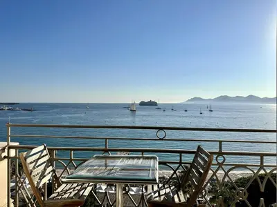 a table and chairs sitting next to the water at Cannes Croisette - Appartement 5 pièces face mer in Cannes