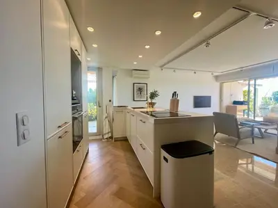 a kitchen with white cabinets and a dining room at Le Bluebay - Luxurious 2 bedrooms seaview swimming pool carpark in Cannes