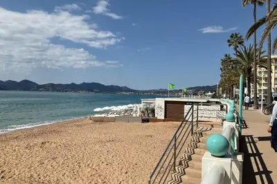 a beach with a building and the ocean at Charming refurbished cocoon with swimming pool in Cannes