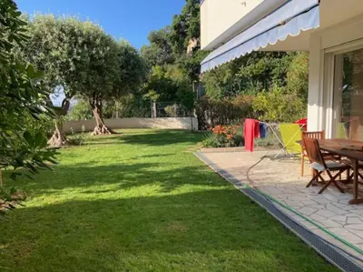 a patio with a table and chairs on a lawn at 3 Pièces avec grand Jardin in Cannes