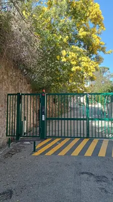 a green gate with yellow stripes in front of a tree at 3 Pièces avec grand Jardin in Cannes