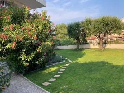a garden with a lawn and some bushes and trees at 3 Pièces avec grand Jardin in Cannes