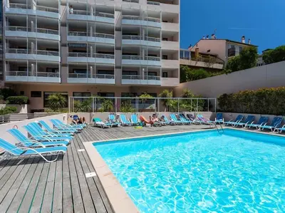 a swimming pool with lounge chairs next to a building at 2 pièces avec piscine, 150 m de la plage. in Cannes
