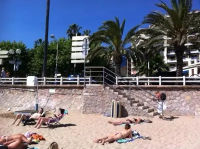 a group of people laying in the sand at the beach at 2 pièces avec piscine, 150 m de la plage. in Cannes
