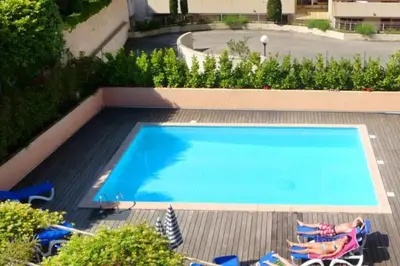 a large swimming pool with chairs at 2 pièces avec piscine, 150 m de la plage. in Cannes