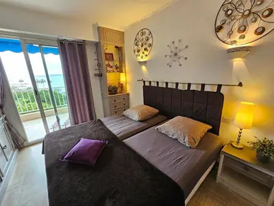 a bedroom with two beds and a balcony at Superbe vue mer à 50 mètres des plages in Cannes