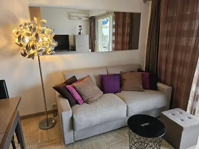 a living room with a couch with colorful pillows at Superbe vue mer à 50 mètres des plages in Cannes