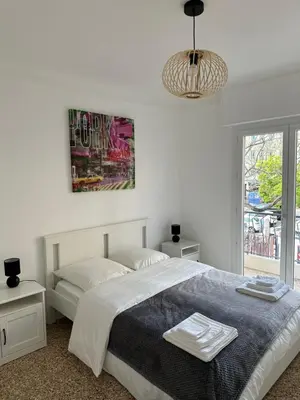 a white bedroom with a bed and a large window at Appartement Cannes in Cannes