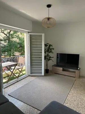 a living room with a tv and a sliding glass door at Appartement Cannes in Cannes