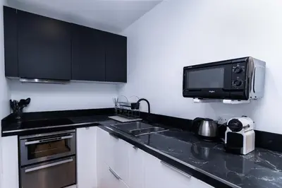 a kitchen with black cabinets and a microwave at Merveilleux appartement - Proche de la Croisette ! in Cannes