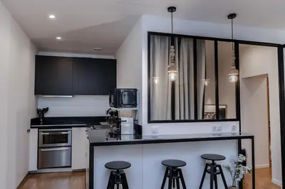 a kitchen with black and white cabinets and bar stools at Merveilleux appartement - Proche de la Croisette ! in Cannes