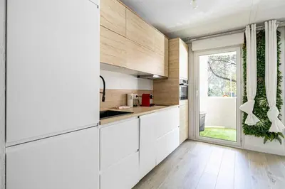 a kitchen with white cabinets and a large window at Comfort and serenity with A-C, Parking and Balcony in Cannes