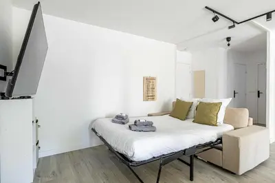 a white bedroom with a bed and a tv at Comfort and serenity with A-C, Parking and Balcony in Cannes