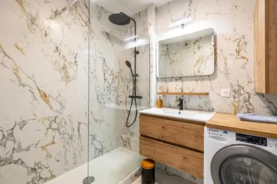 a bathroom with a shower and a sink and a washing machine at Comfort and serenity with A-C, Parking and Balcony in Cannes