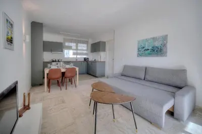 a living room with a couch and a table and a kitchen at Immogroom - cosy apartment - Terrace - AC - Wifi in Cannes