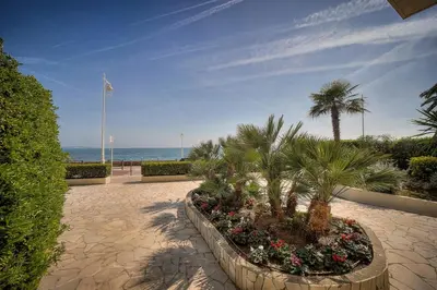 a walkway with palm trees and flowers on the beach at Immogroom - cosy apartment - Terrace - AC - Wifi in Cannes