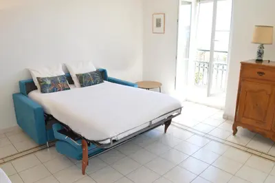 a bed in a room with a blue couch at Appartement vue mer proches plages et congrès in Cannes