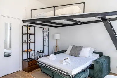 a bedroom with a bunk bed with white sheets at 34 BORNIOL - Bel appartement rénové avec mezzanine Cannes in Cannes
