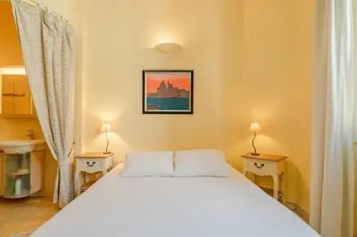 a bedroom with a white bed with two tables and two lamps at Cozystay 1669 Old Port View Elegant 3-Bedroom Apartment in Cannes