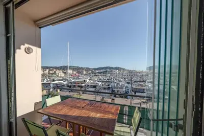 a balcony with a table and a view of a harbor at Cozystay 1669 Old Port View Elegant 3-Bedroom Apartment in Cannes