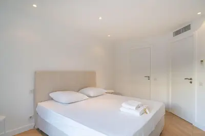 a white bedroom with a bed with two towels on it at Magnificent 2 bedroom in the heart of Cannes in Cannes