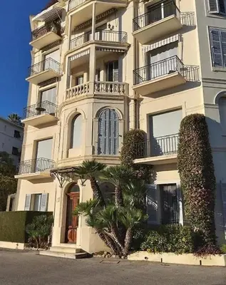 a tall building with a palm tree in front of it at Villa Luna Nova in Cannes